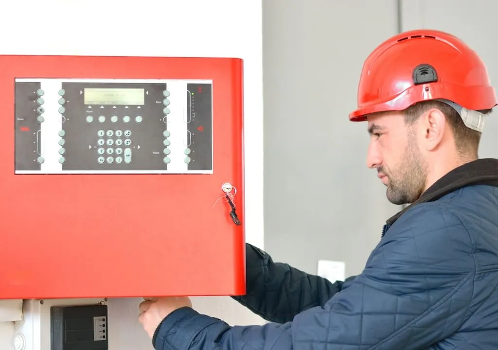 Technician performing routine maintenance on a commercial fire alarm panel.